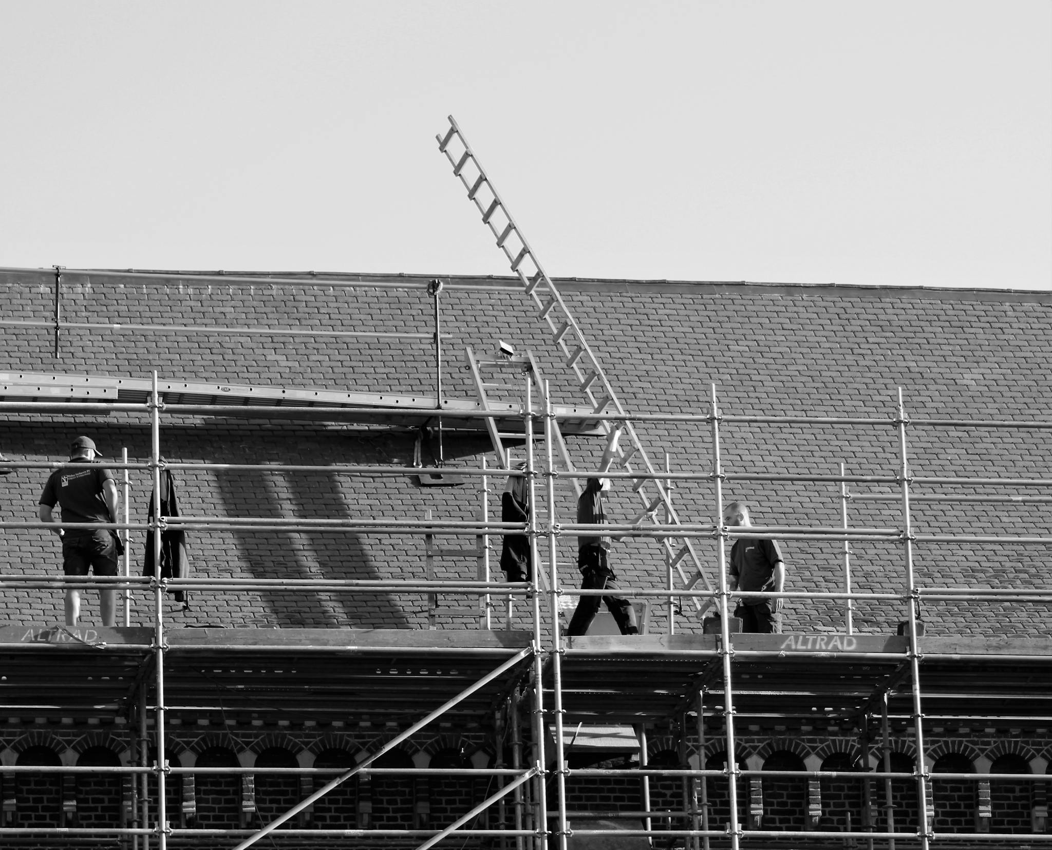 Black and white scene of construction workers renovating a building with scaffolding.